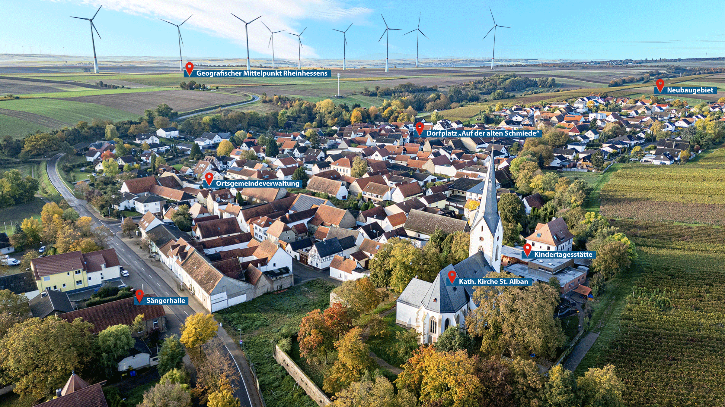 Das Foto zeigt die Ortsgemeinde Gabsheim von oben, mit Positionsmarkierungen elementarer Einrichtungen, wie die Sängerhalle, Gemeindeverwaltung, Kirche St. Alban, Kindertagesstätte, den Dorfplatz und das Neubaugebiet.